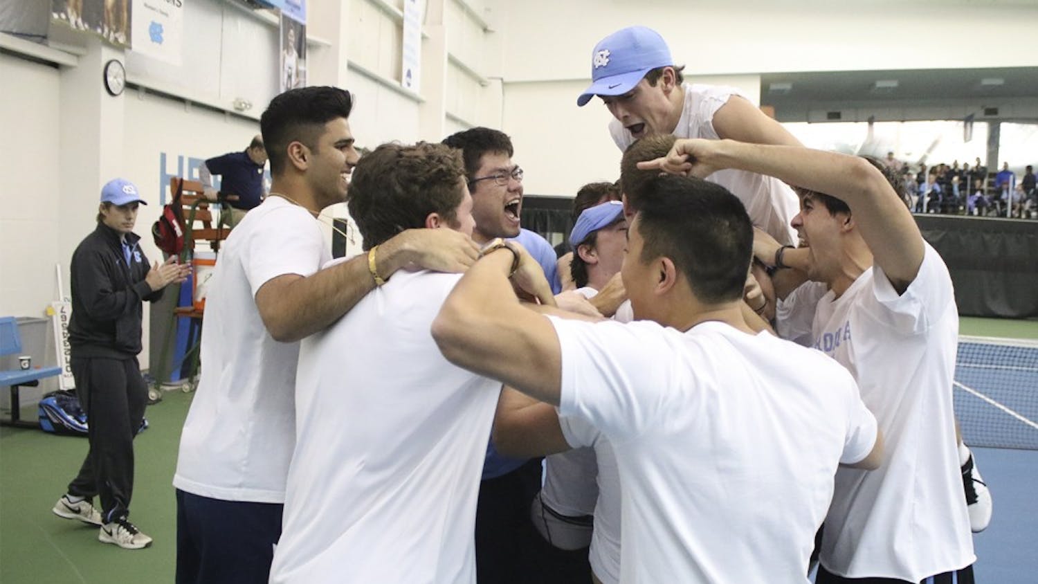 No. 7 UNC Men's Tennis team mobs senior Brett Clark after he won his match in three sets to secure the team's victory over No.5 Oklahoma 4-3 Sunday afternoon.