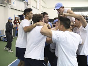 No. 7 UNC Men's Tennis team mobs senior Brett Clark after he won his match in three sets to secure the team's victory over No.5 Oklahoma 4-3 Sunday afternoon.
