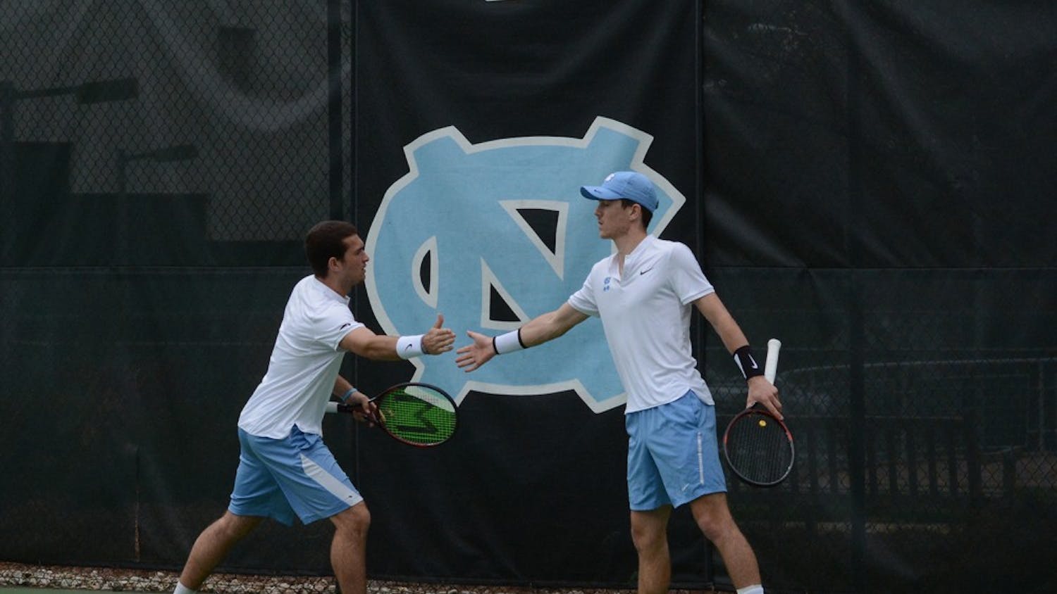 Will Blumberg (left) high fives doubles partner Robert Kelly (right) in Saturday’s doubles match against Tulsa.