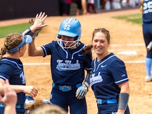 The UNC softball team celebrates at the dugout during the game against Florida State at Anderson Stadium on Saturday, April 16, 2022. UNC won 5-1.