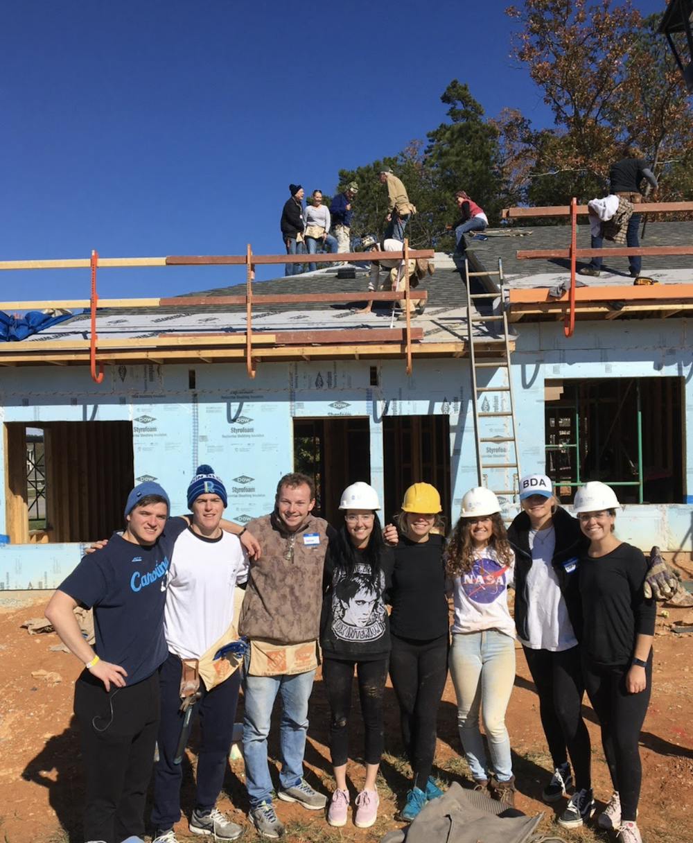 <p>Workers pose in front of a Habitat for Humanity work site while others do work on the roof. Arts for Humanity is putting on a virtual art show to benefit Habitat. Photo courtesy of Claire Hyde.</p>