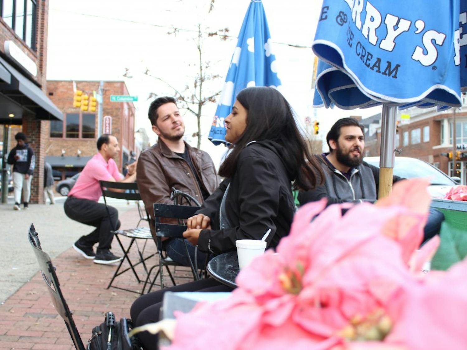 The Chapel Hill Town Planning Commission is considering changing the sidewalk dining ordinance to expand seating. Adam James, David Alki, and Aditi Patel sit outside of Ben and Jerry's on Franklin Street Thursday, March 21, 2019.