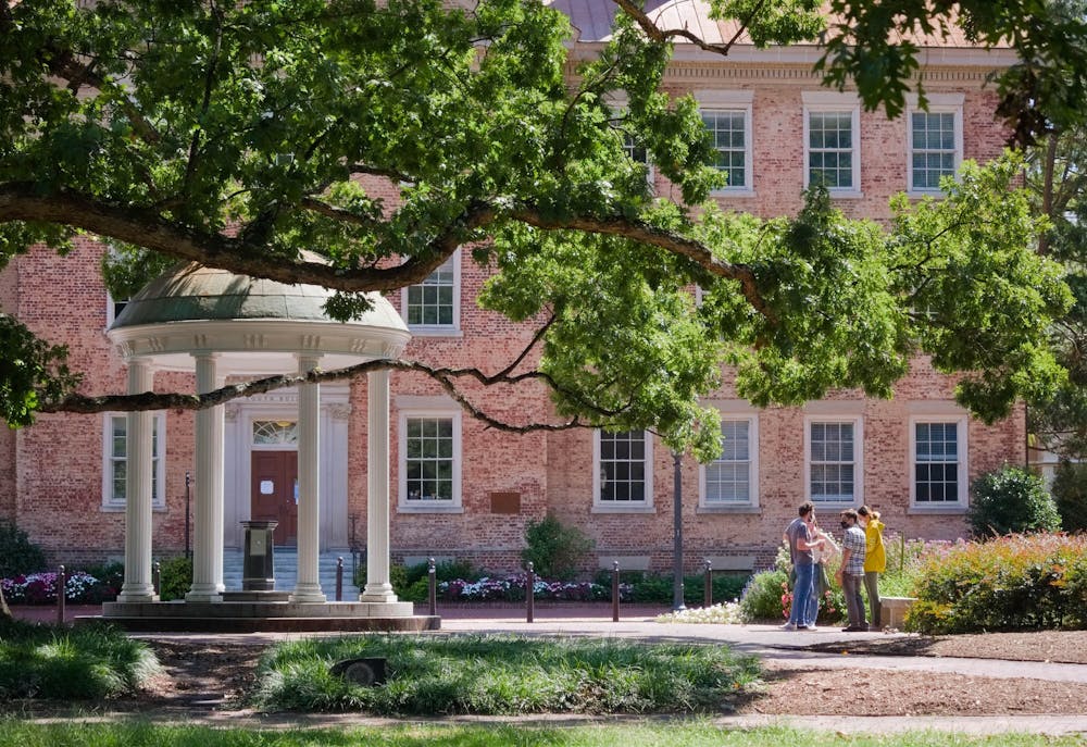 <p>A small group stands near the Old Well behind South Building on Sept. 12, 2020.</p>
