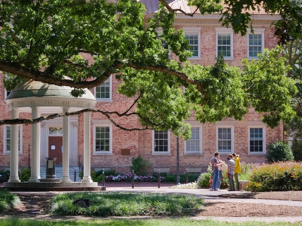 A small group stands near the Old Well behind South Building on Sept. 12, 2020.