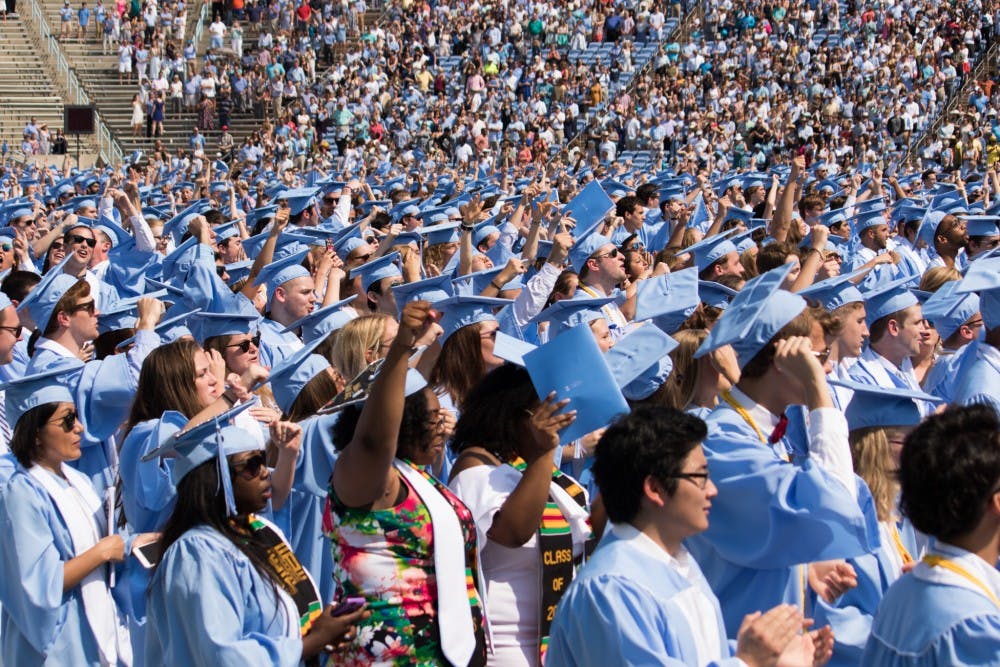 Students raise their fists at the end of "Hark the Sound" during Commencement on May 13.&nbsp;
