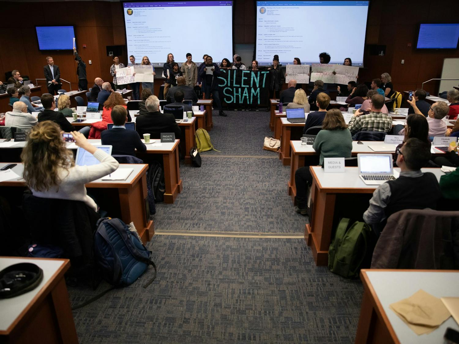 Activists make demands for Interim Chancellor Kevin Guskiewicz on the floor of the Faculty Governance Council for "Reparations, retract or resign" on Friday, Dec. 6, 2019 in Kerr Hall. They referred to a settlement between the University and the Sons of Confederate Veterans to give the SCV Silent Sam and a trust fund of $2.5 million.