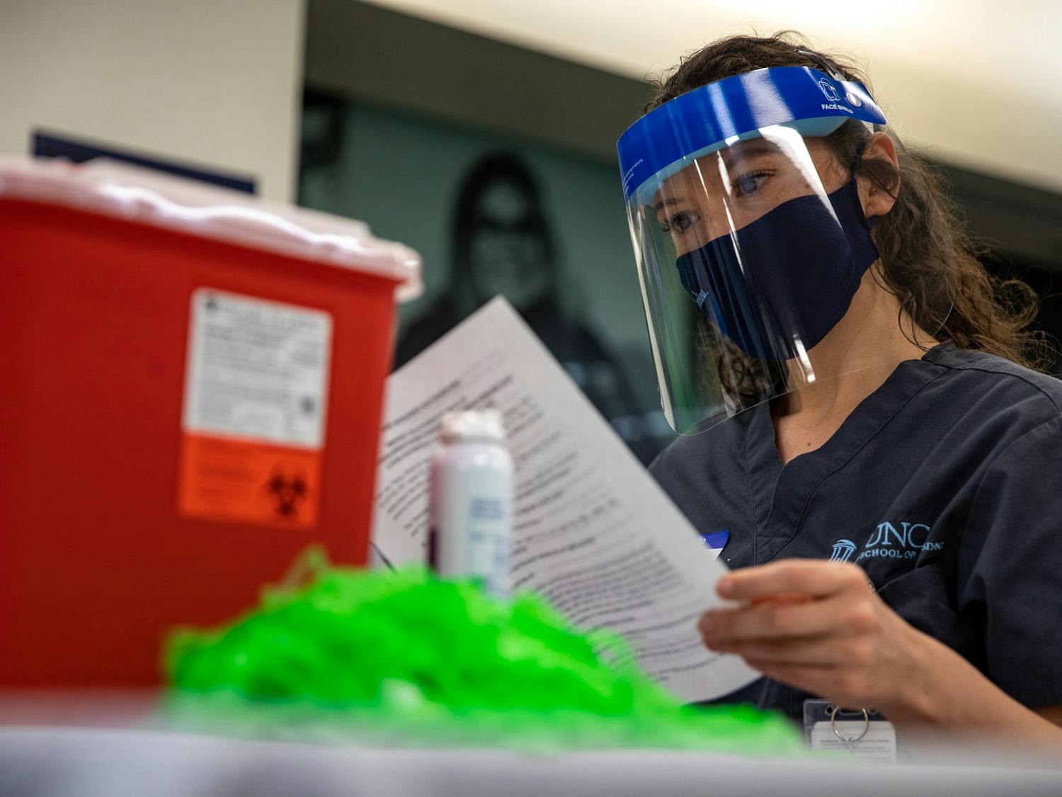 A vaccine administrator reads an information packet in the Student Union on March 31, 2021. As North Carolina began to allow college students to receive coronavirus vaccines, UNC opened a clinic on campus where students can receive the Johnson & Johnson vaccine.