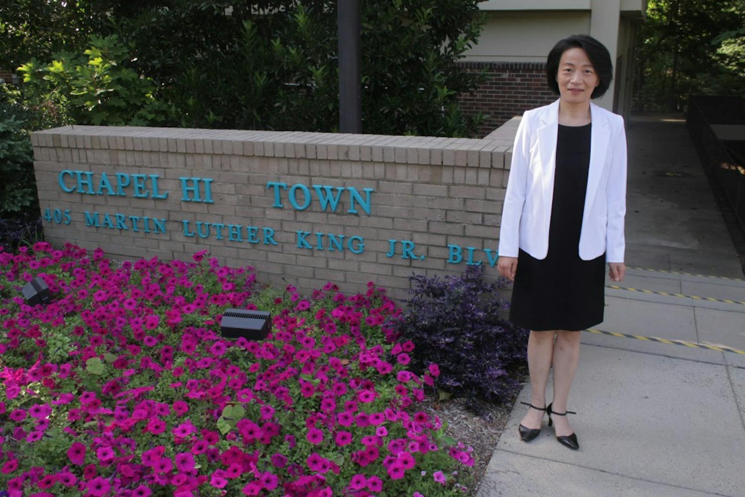 Chapel Hill town council candidate Hongbin Gu poses for a portrait in front of the Chapel Hill Town Hall building.