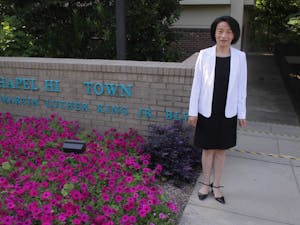 Chapel Hill town council candidate Hongbin Gu poses for a portrait in front of the Chapel Hill Town Hall building.