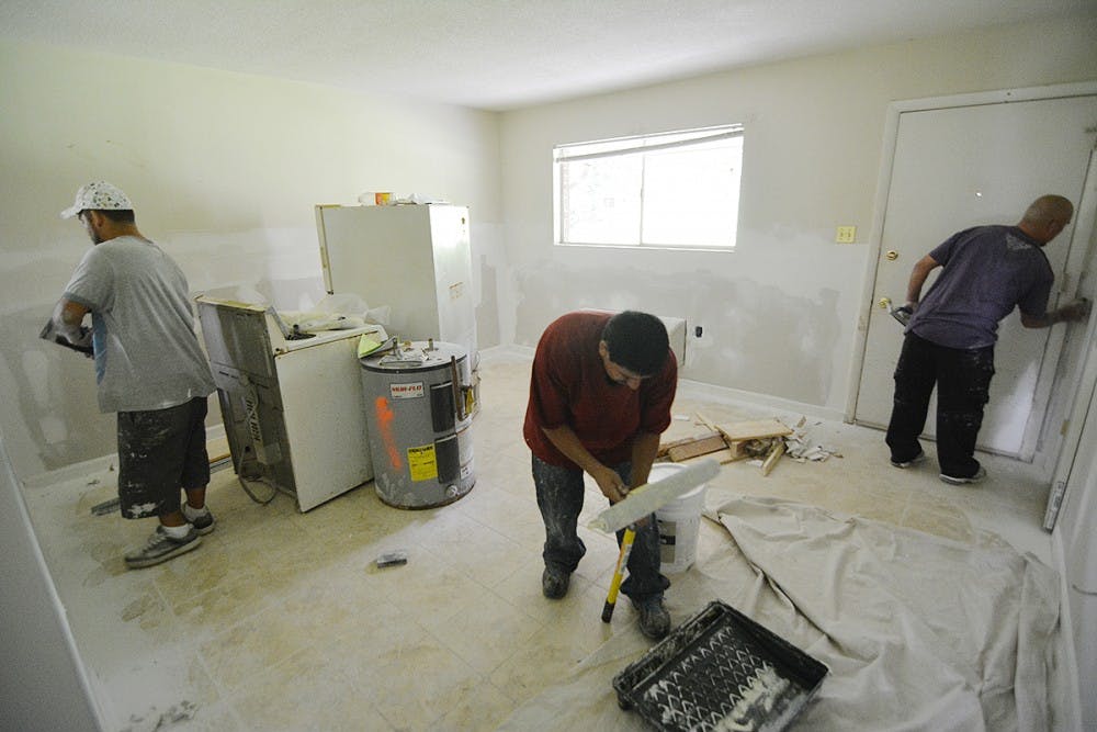 Brothers, Jay Lopez (left), Oscar Lopez, and Luis Lopez work on renovating the condemned apartments at Camelot Village.