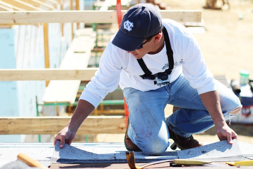 	<p>Burgess Robinson, a studio art and physics major, nails shingles on the roof of a Habitat for Humanity house during the ‘Blitz Build’ on Saturday.</p>