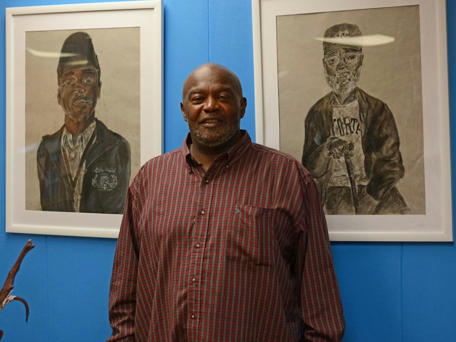 Anthony Sharp stands next to artwork at the CEF office - he is currently organizing an art show with the office to be featured in the Ackland and Campus Y in April. 
