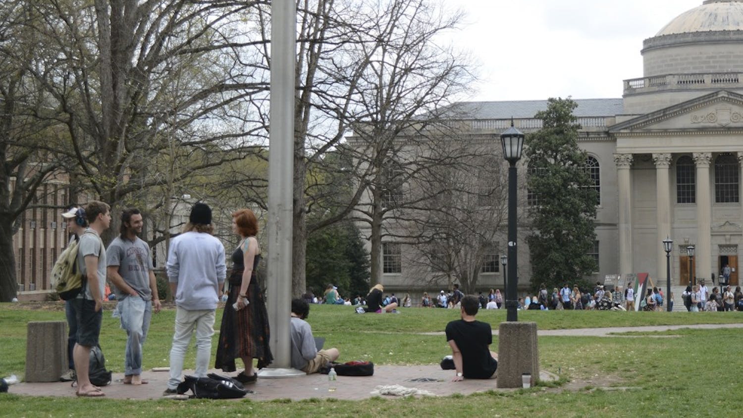 Students smoke and converse around the flagpole on the Lower Quad. 