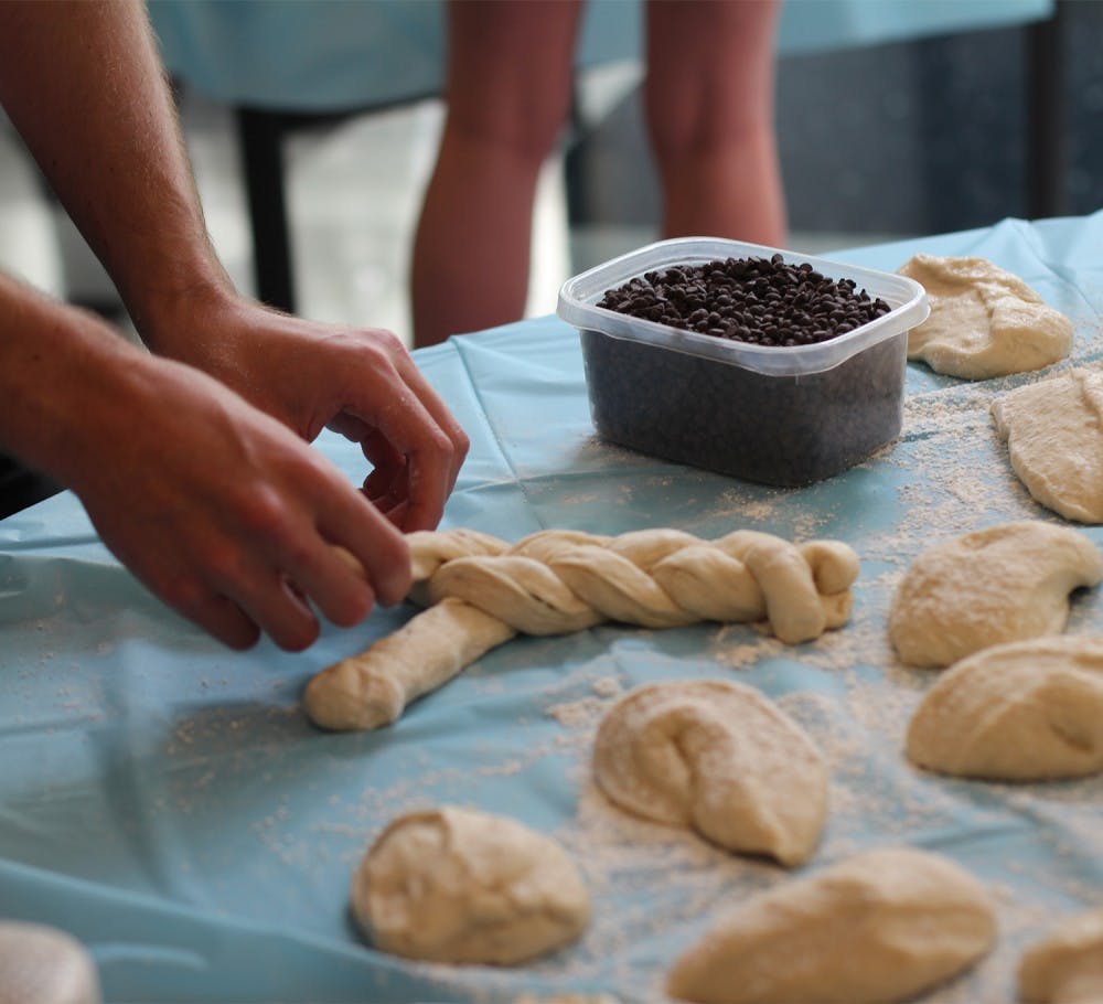 <p>Students weave dough for the Challah for Hunger bake sale. Challah is a traditional Jewish bread eaten on Sabbath and holidays. </p>