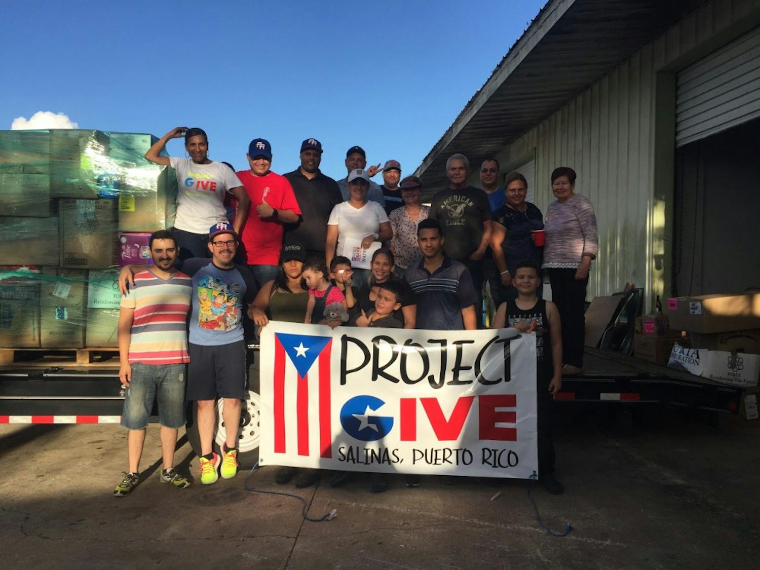 Members of the groups pose together in front of the food and supplies they've gathered for Puerto Rico. Photo courtesy of Jose Cartagena. 