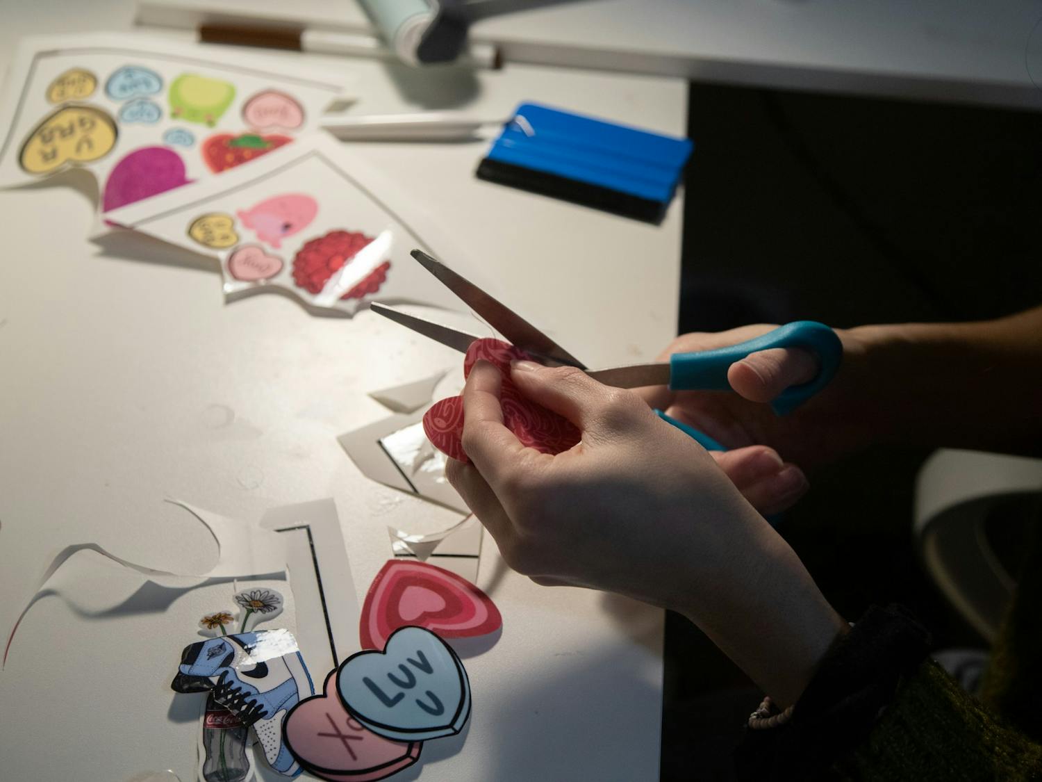 Senior Marina Carolina Fela-Castillo cuts out a heart sticker from her Valentine's Day collection on Monday, Feb. 15, 2021. Fela-Castillo is the owner and creative behind Pintamar.