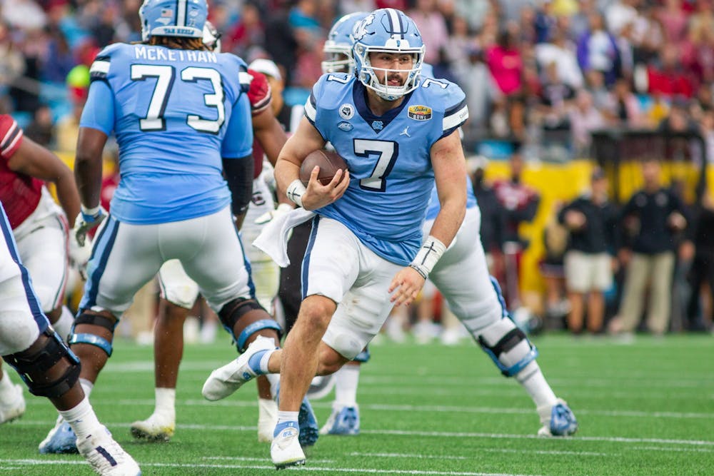Junior quarterback Sam Howell (7) carries the ball at the Duke's Mayo Bowl against South Carolina at the Bank of America Stadium in Charlotte on Dec. 30, 2021. UNC lost 21-38.