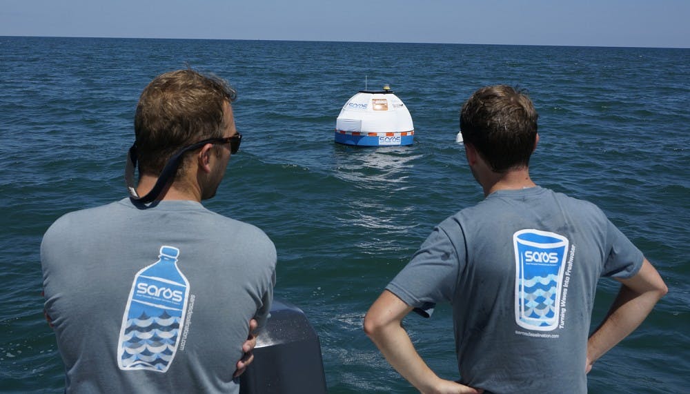 Chris Matthews (left) and Justin Sonnett, co-founders of Saros, watch their invention, a wave powered buoy that desalinates water and makes it clean to drink. Photo Courtesy of Saros.