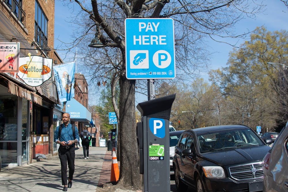 Pedestrians pass a parking meter on Franklin Street on Tuesday, March 21, 2023.