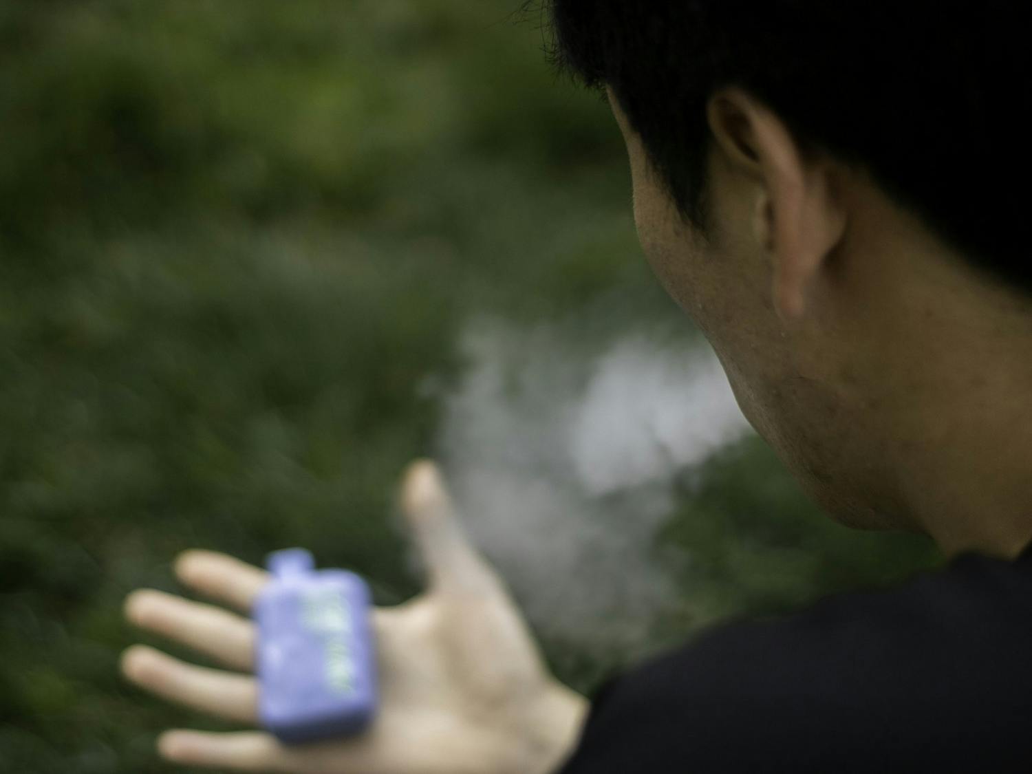 A UNC student vapes at Polk Place on Wednesday, April 5, 2023.