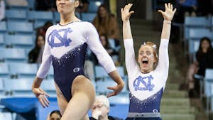 Junior Jamie Shearer celebrates sophomore Julia Knower's floor routine during Carolina Gymnastics' home tri-meet on Monday, Jan. 23, 2023.