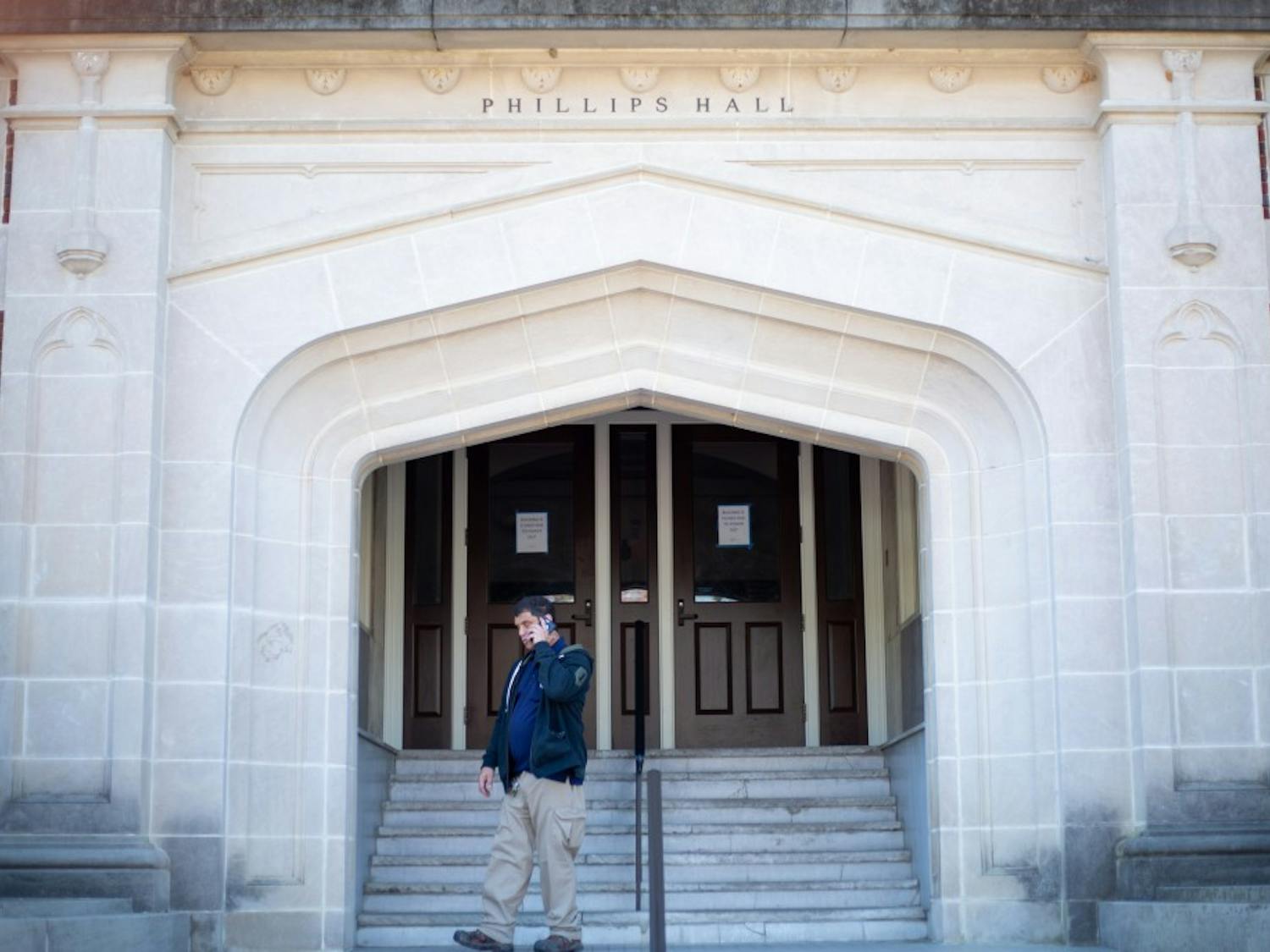 Chris Moore, a utility worker at UNC, takes a phone call outside Phillips Hall where he is on duty to inform students not to enter on April 3, 2019 due to flooding and a power outage.
