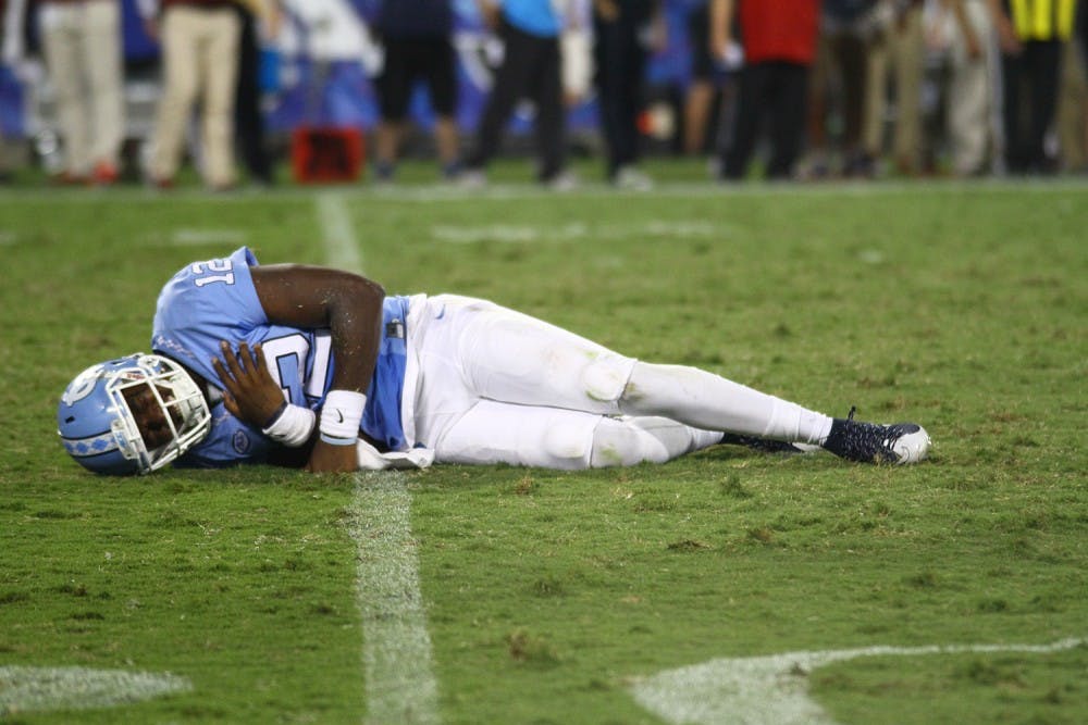 <p>North Carolina senior quarterback Marquise Williams (12) grimaces after a hard hit to the shoulder. Williams was sacked four times in Thursday night’s loss.</p>