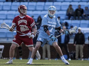 UNC junior midfielder Tanner Cook (77) fends the ball from Denver junior midfielder Kyle Smith (21) during UNC's 12-10 home loss against the University of Denver on Saturday, March 3, 2019 at the UNC Soccer and Lacrosse Stadium in Chapel Hill, N.C. This was the UNC Men's Lacrosse team's inaugural game at the UNC Soccer and Lacrosse Stadium.