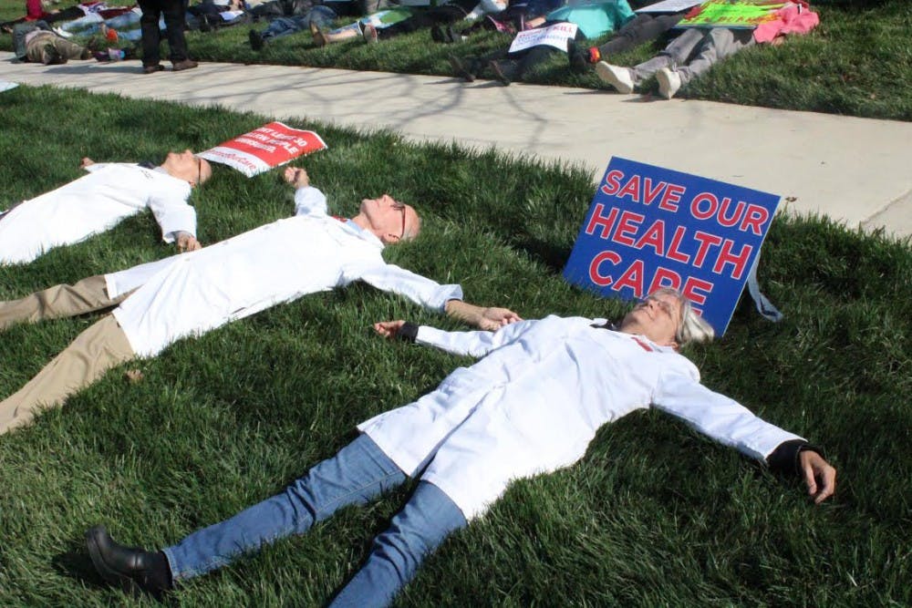 <p>Participants spread out in the grass during Friday’s die-in in Durham in reaction to the possible changes in health care policies.</p>