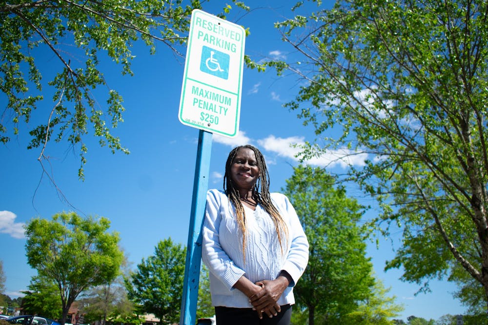 <p>Darice Johnson, a disabled veteran, is pictured with an accessible parking sign on Tuesday, April 19, 2022.</p>