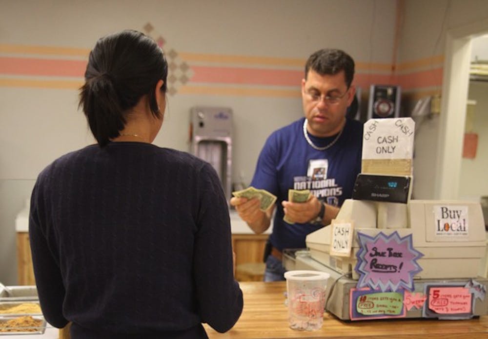 Yogurt Pump employee houman ebrahimi counts out change for a customer Monday. the Yogurt Pump,
like several other area businesses including Bub o’Malley’s and expressions, only accepts cash payments.