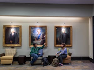 Kerry McIntyre and Rohit Sharma, students of the MBA class of 2023, engage in conversation in the lobby of McColl Building on Monday, Oct. 3, 2022. Hanging behind them are the portraits of Hugh L. McColl, Jr., Mary Lily Kenan, and Henry Flagler, the namesakes of &nbsp;McColl Building and Kenan-Flagler Business School.