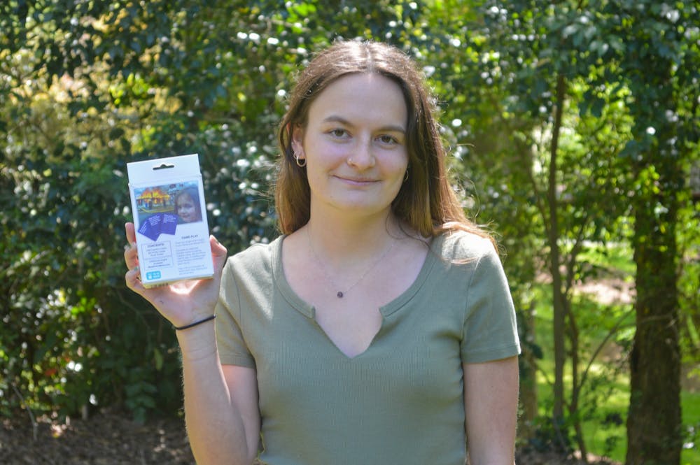 Zoe Roth, a senior peace war and defense major and subject of the meme 'Disaster Girl', holds up the card game What Do You Meme? on Tuesday Apr 13, 2021 in Chapel Hill.