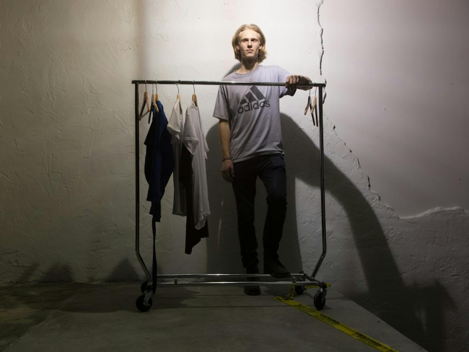 James Creissen, a sophomore business major, poses in front of a rack of clothes he designed. Creissen held a fashion show on East Rosemary Street Thursday night.&nbsp;