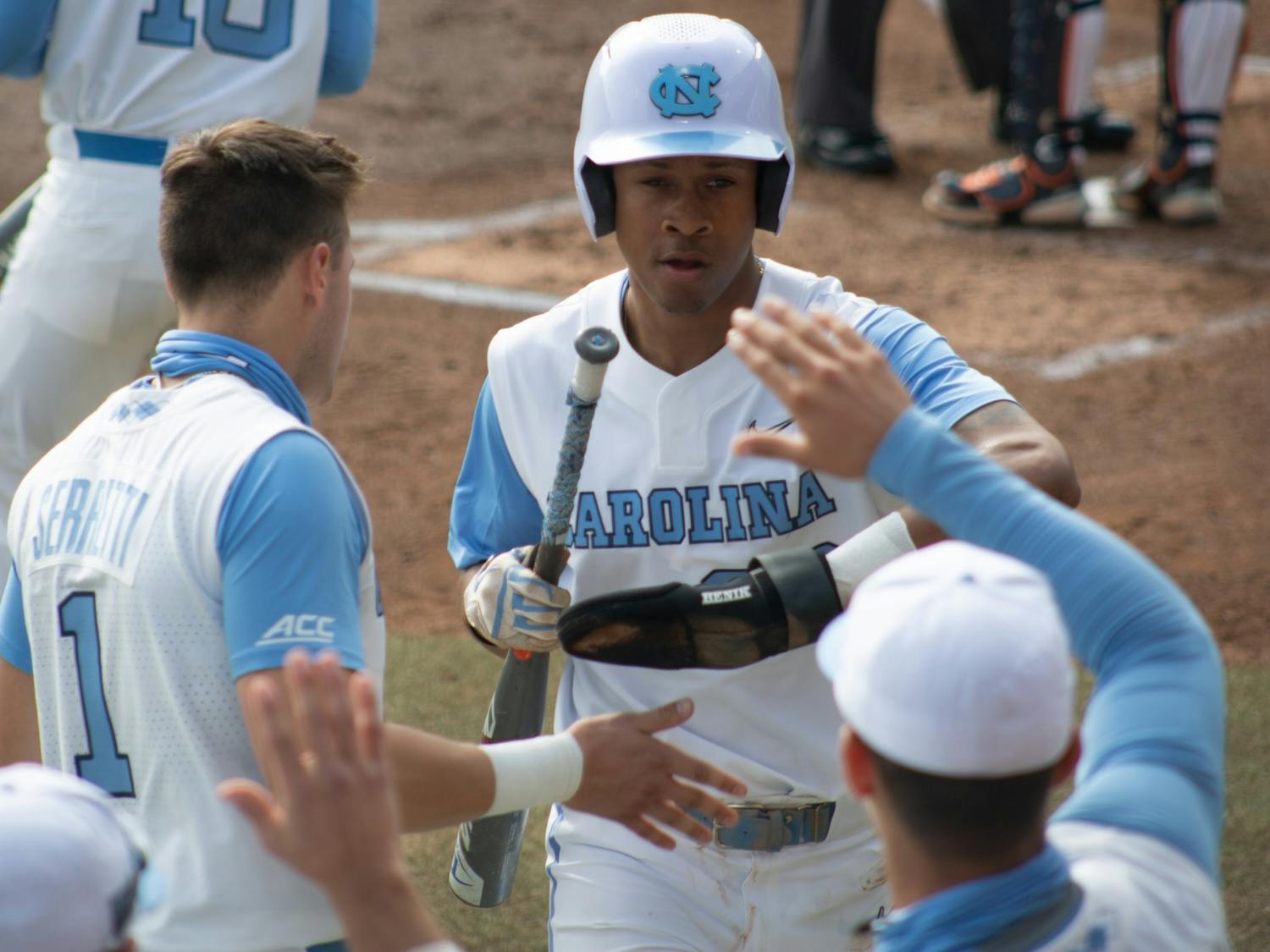 Sophomore outfielder Justice Thompson (20) gets high fives from teammates after stealing home against University of Virginia on Saturday, Feb. 27, 2021. The Tar Heels beat the Cavliers 2-1.