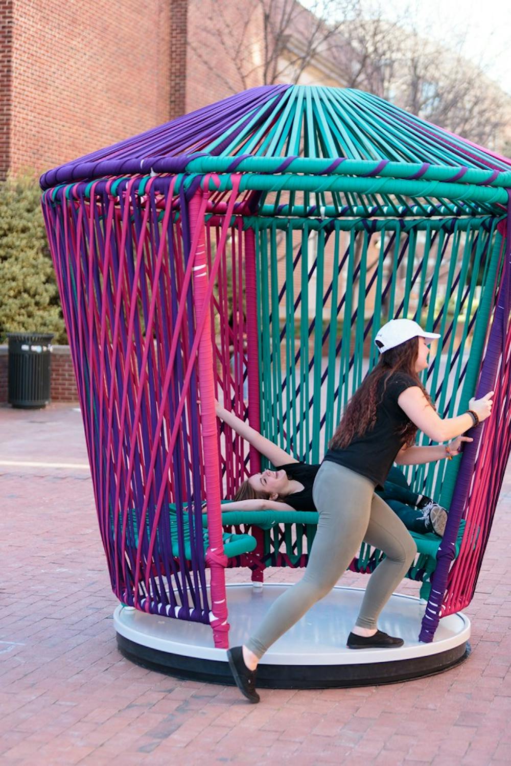 First year dramatic art and journalism major  Amy Cockerham (left) and first year psychology major Madison Robertson spin on one of the new structures outside Davis library.