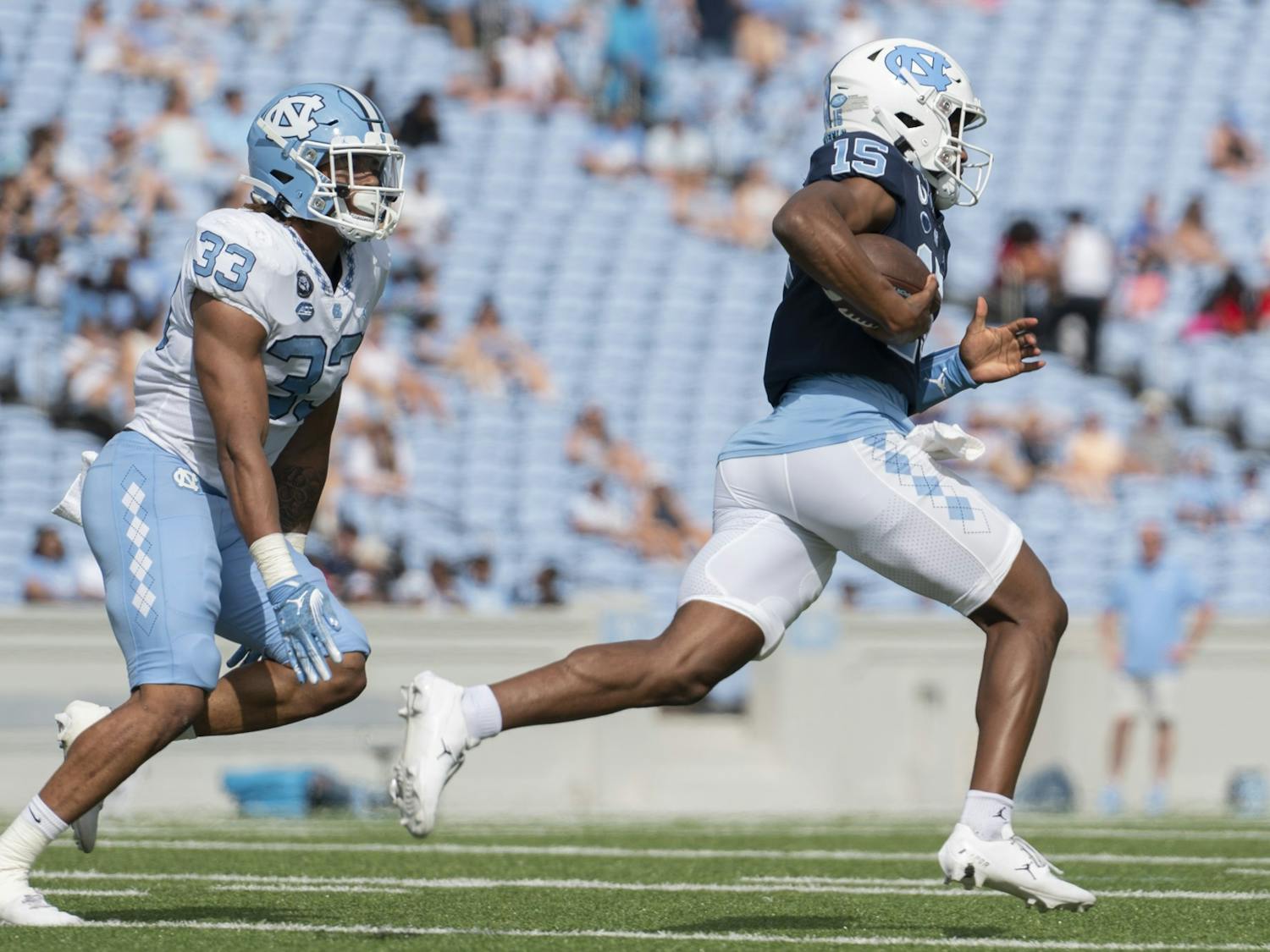 UNC senior linebacker Cedric Gray (33) chases after UNC first-year quarterback Connor Harrell (15) as he runs down the line during the Spring Game in Kenan Stadium at on Saturday, April 15, 2023.&nbsp;