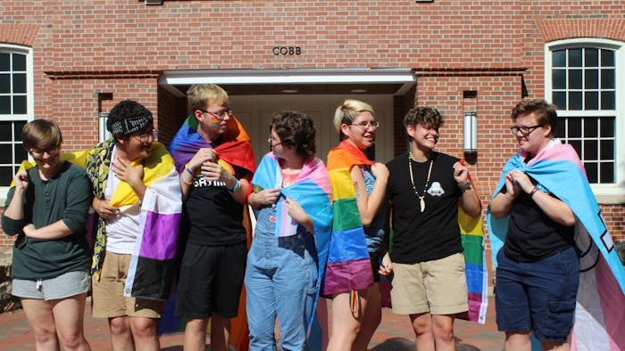 A group of students stand in front of Cobb Community on Sunday, Sept. 28, 2019. They hold flags for different groups within the LGBTQ+ community.
