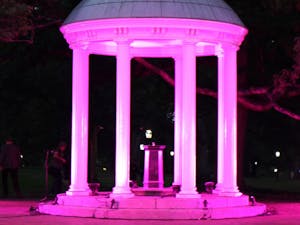 The Old Well stands illuminated with pink lights for the first time in honor of Breast Cancer Awareness month during the Pink out Polk Place event put on by the UNC Lineberger Comprehensive Cancer Center. The event included a fun run where the first 100 runners were covered in pink and blue powder. 