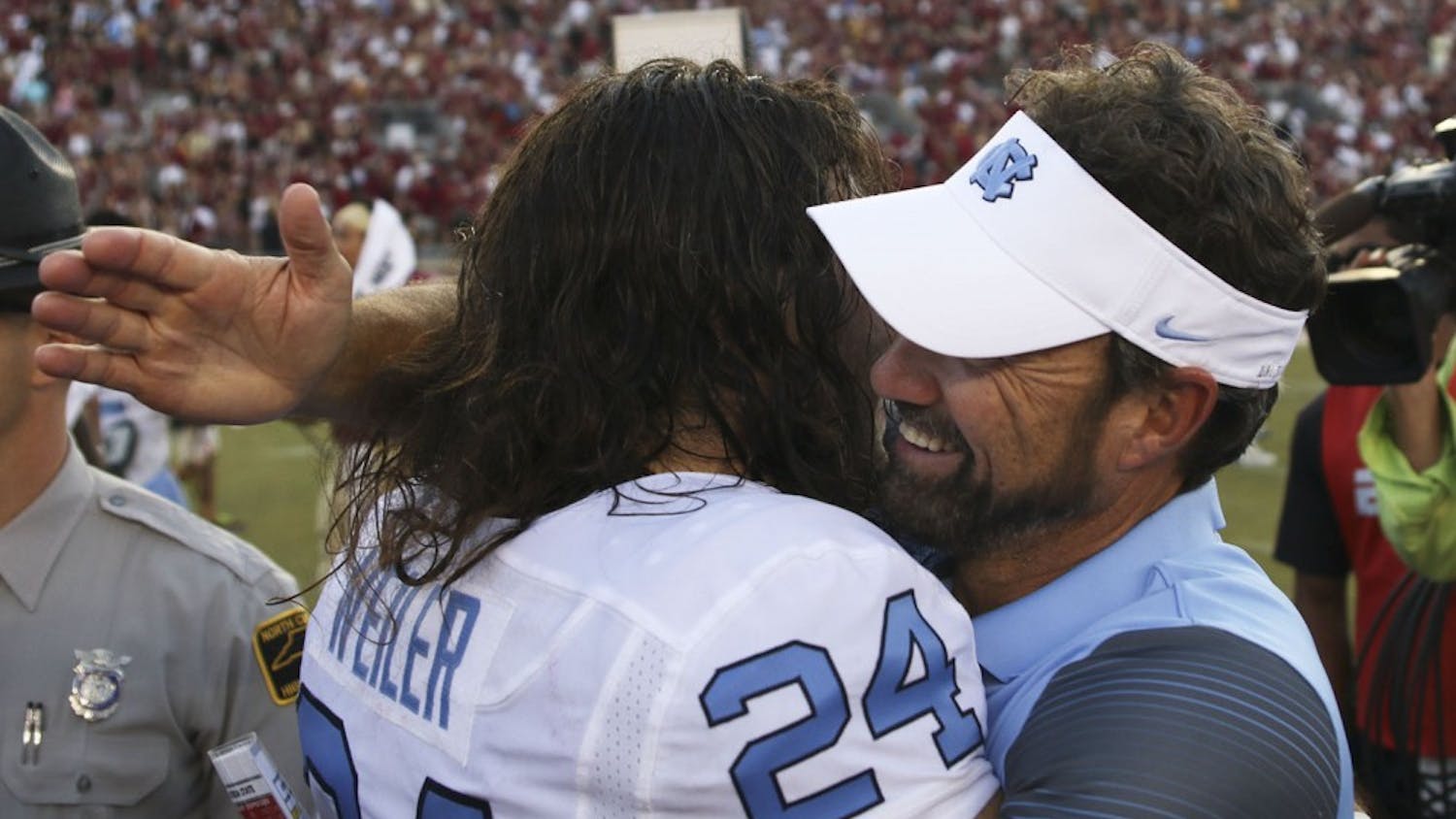 UNC kicker Nick Weiler (24) embraces head coach Larry Fedora after the team's dramatic win over Florida State.