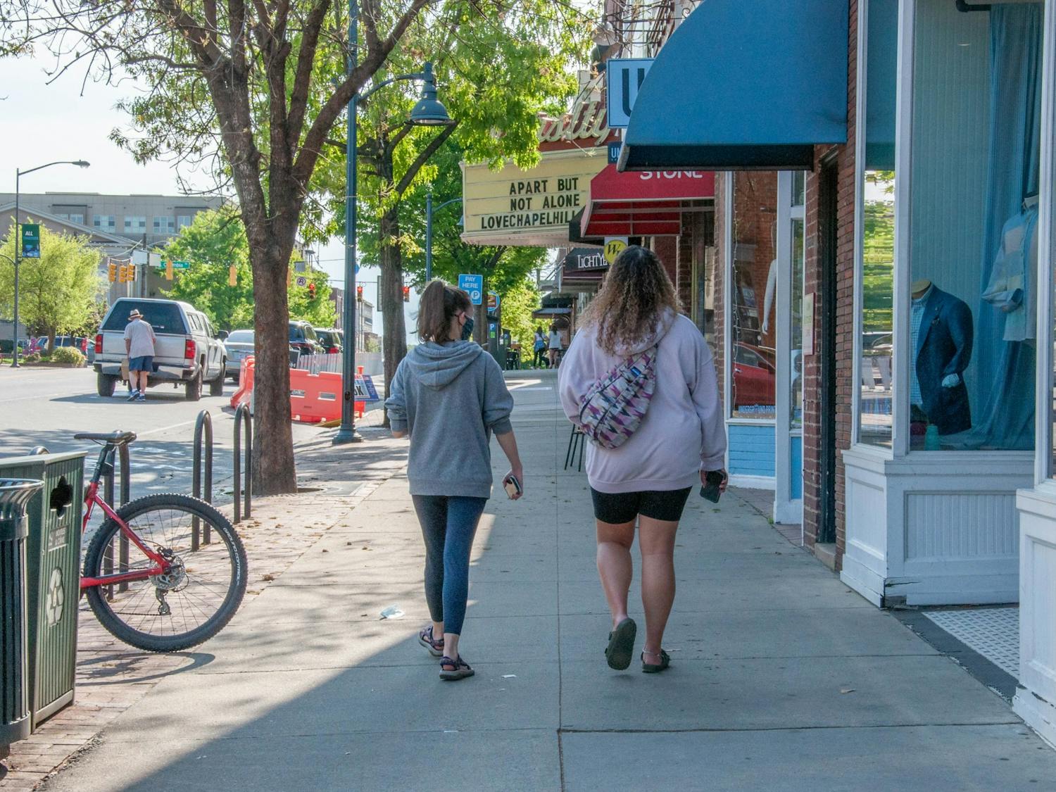 Two students walk on Franklin Street in Chapel Hill on April 13, 2021