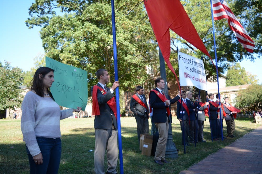 Aryana Bolourian (left), a senior economics and public policy major, holds a "Women's rights experts" sign pointing at the demonstrators.