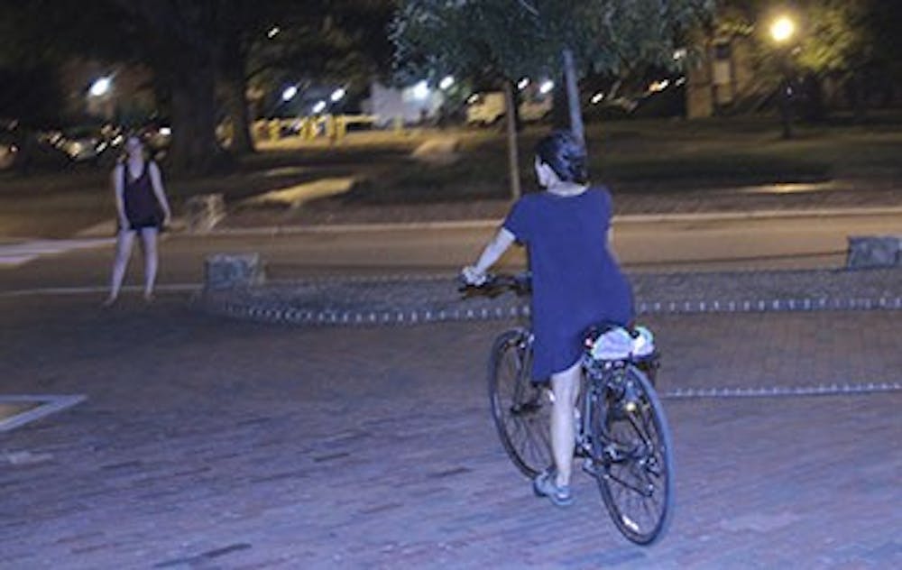 Senior Global Studies major&nbsp;Eileen Harvey rides her bike in front of Memorial hall on Thursday night.