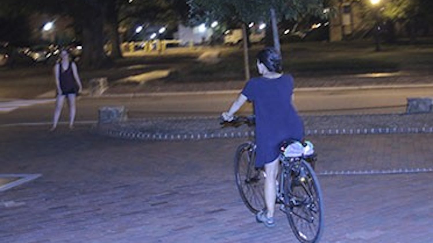 Senior Global Studies major&nbsp;Eileen Harvey rides her bike in front of Memorial hall on Thursday night.