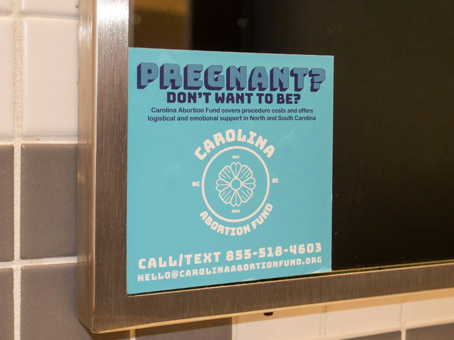 A sticker for Carolina Abortion Fund draws attention to their services in a women's bathroom on UNC's campus. 