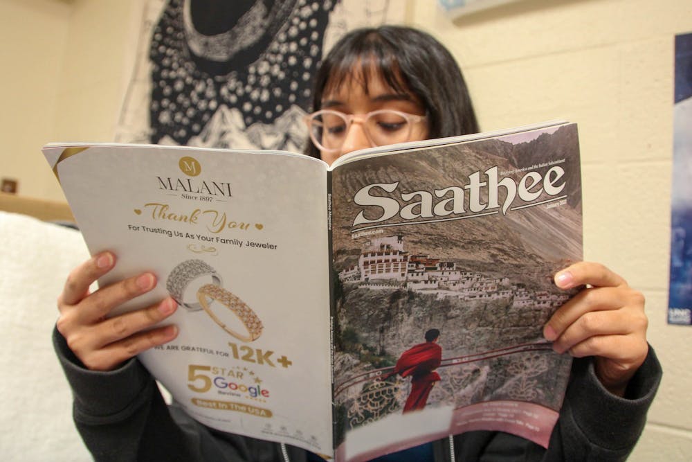 DTH Photo Illustration. A student reads the January 2022 edition of Saathee.