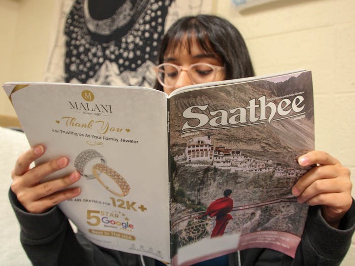 DTH Photo Illustration. A student reads the January 2022 edition of Saathee.