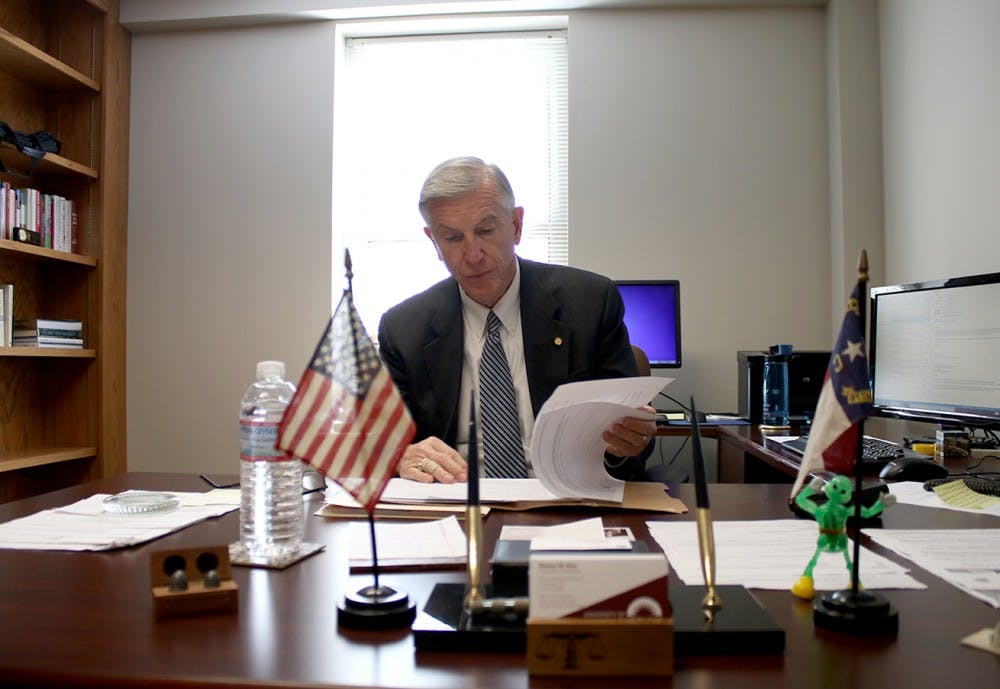 Former UNC-System President, Tom Ross, glances at documents in his office.