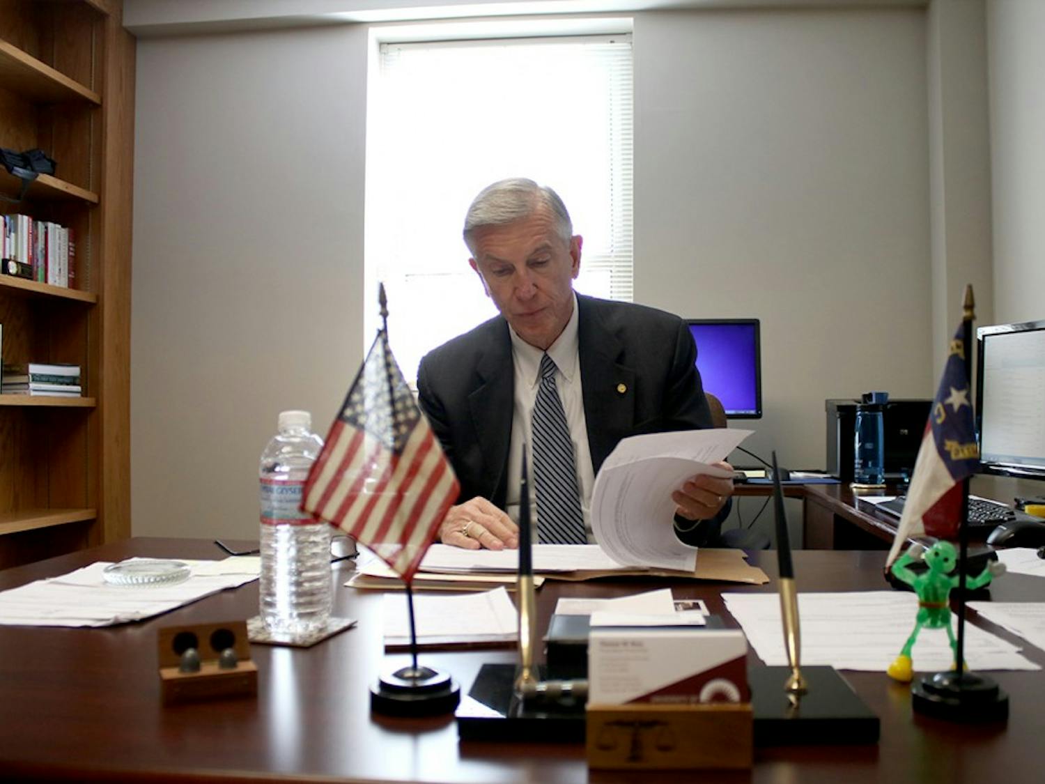 Former UNC-System President, Tom Ross, glances at documents in his office.