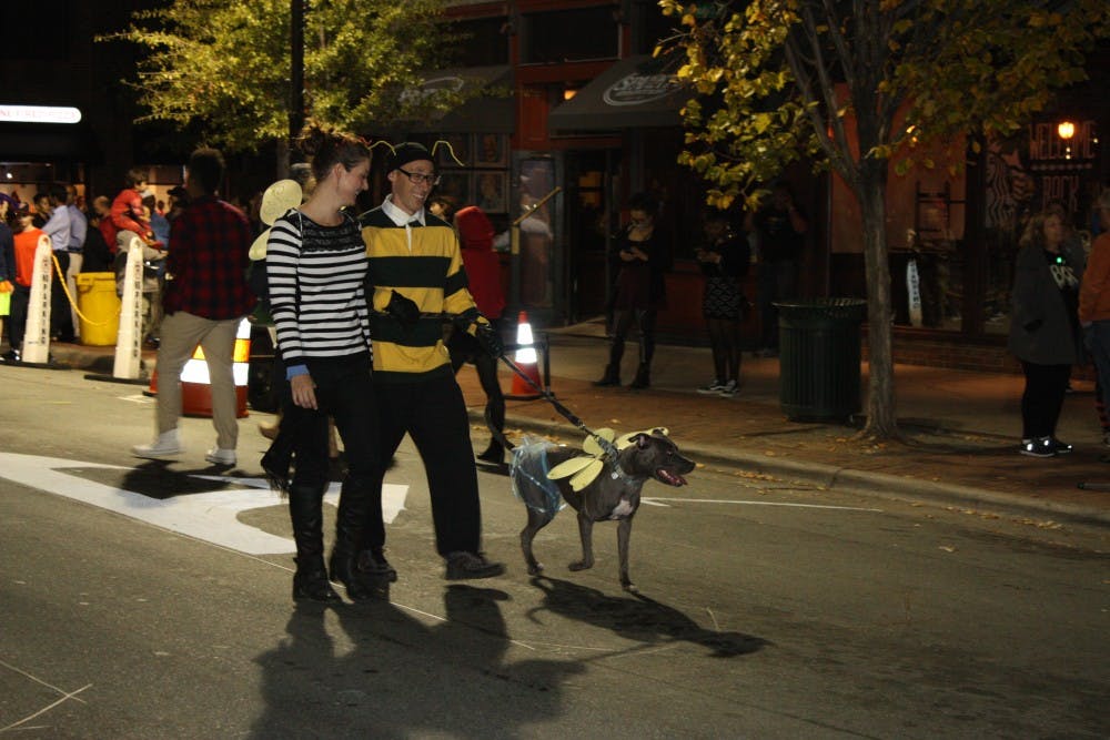 Two individuals walk down Franklin Street with their dog on Halloween night.&nbsp;